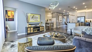 A modern living room with a sofa, coffee table, and decorative items. There is a dining area with a table and chairs, and a kitchen area with appliances. - Tasteful Durham Townhome - 6 Mi to Downtown! (Durham)