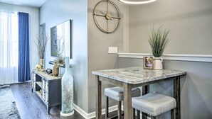 A dining area with a marble table, bench seating, a wall clock, and a potted plant. - Tasteful Durham Townhome - 6 Mi to Downtown! (Durham)