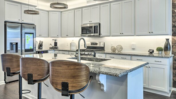 A modern kitchen with white cabinets, stainless steel appliances, a granite countertop, and three wooden bar stools. - Tasteful Durham Townhome - 6 Mi to Downtown! (Durham)