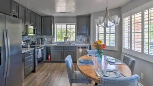 A modern kitchen with grey cabinets, stainless steel appliances, and a wooden dining table set for four.