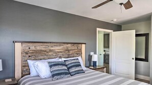 A bedroom with a wooden headboard, a striped bedspread, and a nightstand with a lamp.