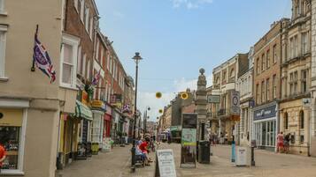 Straatbeeld met winkels, een bord met 'Old Ship Inn' en een reclamebord van 'Dorchester Jewellers & Repairs'.