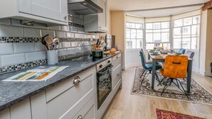 A modern kitchen with white cabinets, a black countertop, and a dining area with a table and chairs.