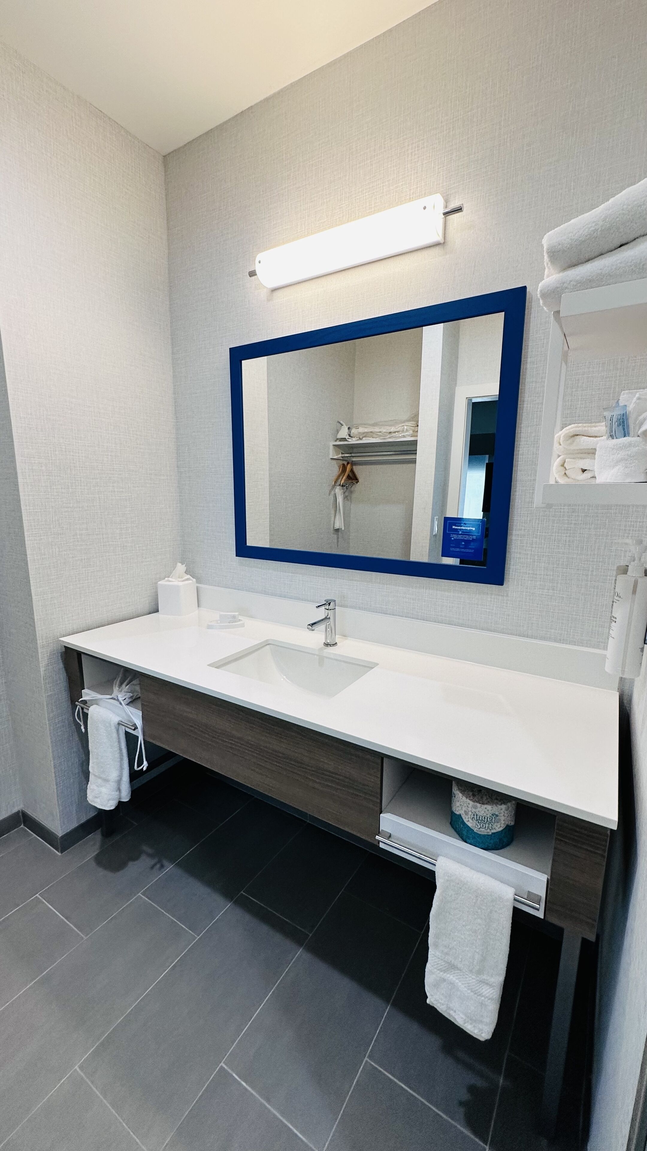 Un bany modern amb un mirall gran, un lavabo blanc i un moble de tocador de fusta fosca.