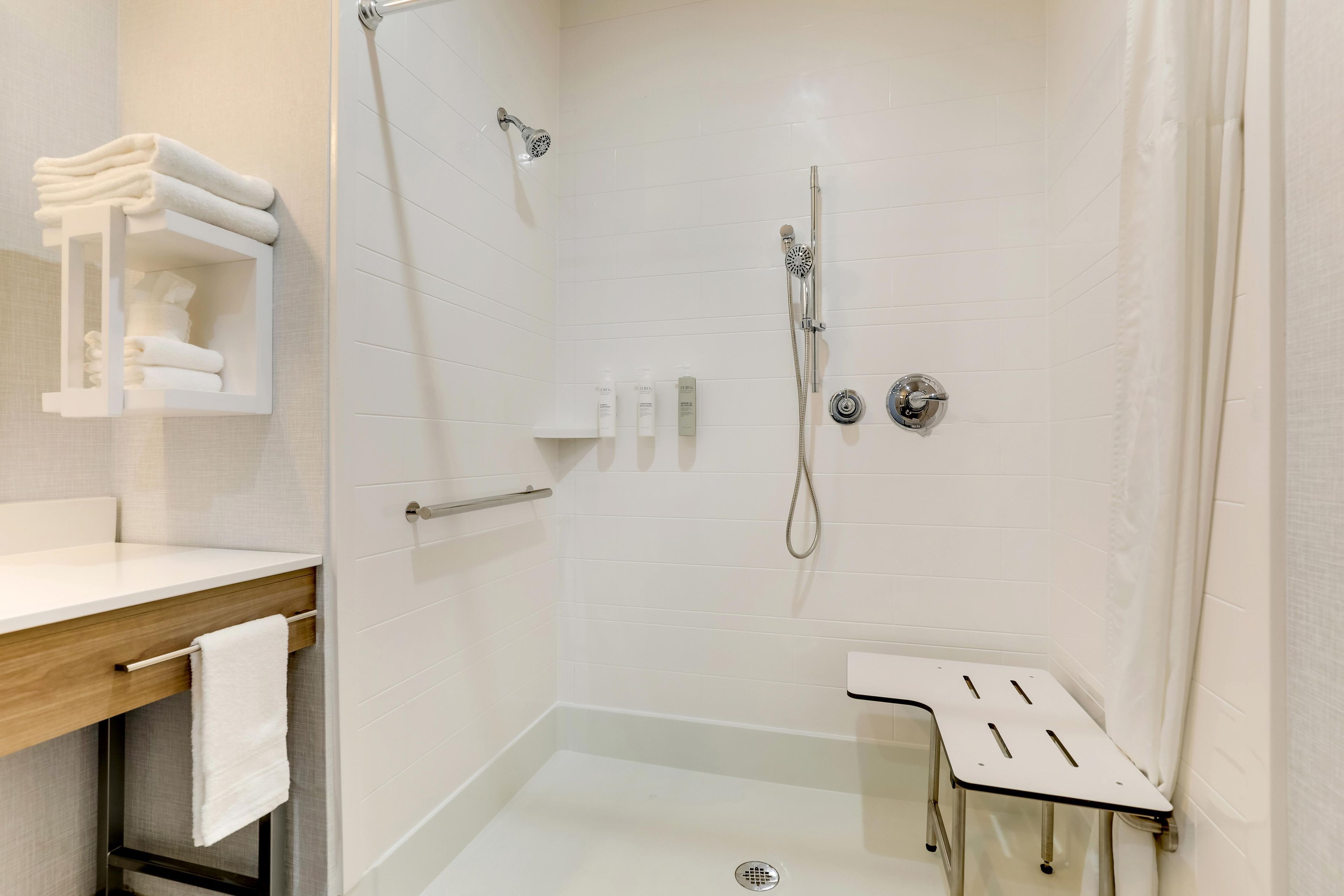 Un baño moderno con ducha, lavamanos y un perchero para toallas.