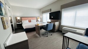 A hotel room with a bed, desk, chair, TV, and a window.