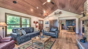 A spacious living room with leather sofas, a wooden coffee table, and a view of the outdoors. - Patio, Views & Hot Tub: Quiet Lakeside Cabin (Grantsburg)