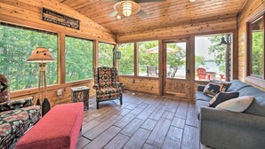 A cabin interior with a wooden ceiling, a ceiling fan, a sofa, a chair, and a table. - Patio, Views & Hot Tub: Quiet Lakeside Cabin (Grantsburg)