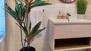 A bathroom with a white vanity, a round mirror, a potted plant, and patterned floor tiles. - The Callie by Sasco Apartments (Blackpool)