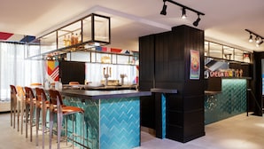 Zona de bar moderna con mostrador, taburetes y una variedad de botellas y vasos.