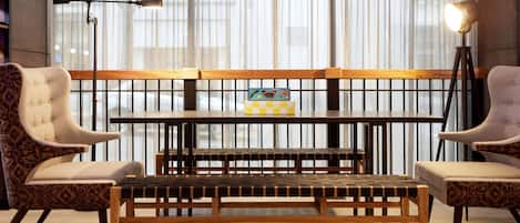 A seating area with a bench and two chairs, a floor lamp, and a window with sheer curtains.
