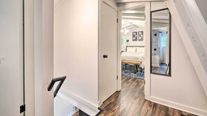 A hallway with a white door, a wooden floor, and a mirror reflecting a bedroom with a bed and a nightstand. - Private Hot Tub & Fire Pit: Family Broadway Cabin (Broadway)