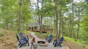 A forested area with a fire pit and Adirondack chairs. - Private Hot Tub & Fire Pit: Family Broadway Cabin (Broadway)
