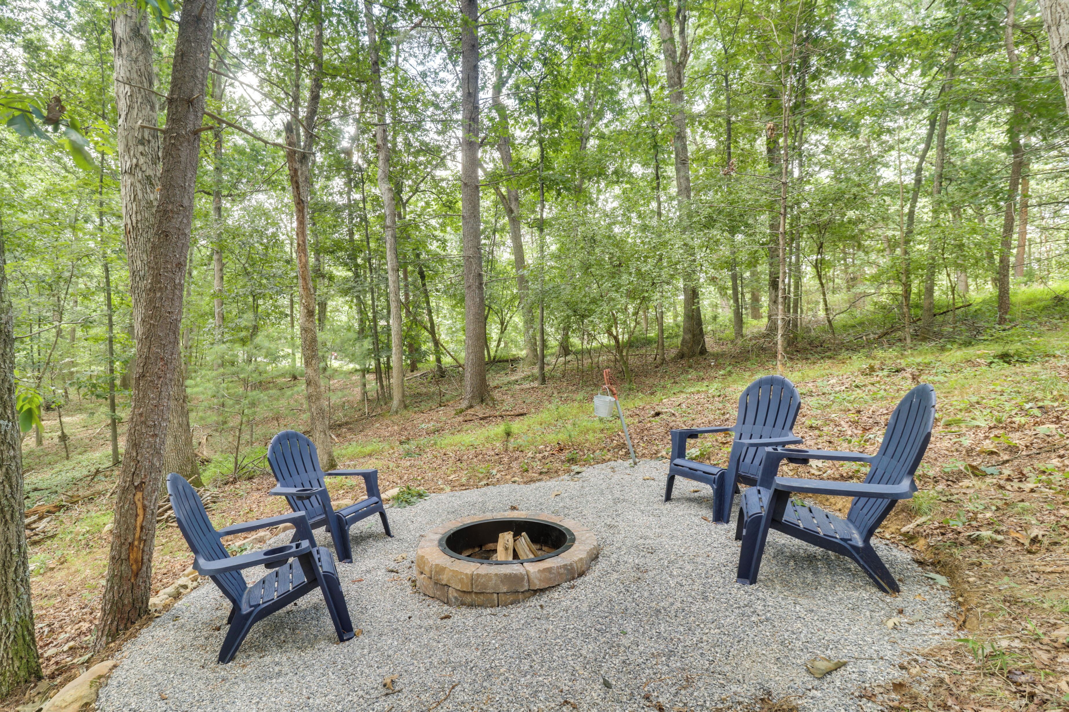 Een bebost gebied met een vuurplaats en Adirondack stoelen.