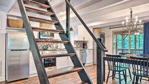 A modern kitchen with a stainless steel refrigerator, a built-in oven, and a dining area with a round table and chairs. - Private Hot Tub & Fire Pit: Family Broadway Cabin (Broadway)