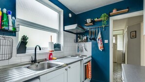 Una cocina moderna con armarios blancos, un lavamanos de acero inoxidable y un ventanal.