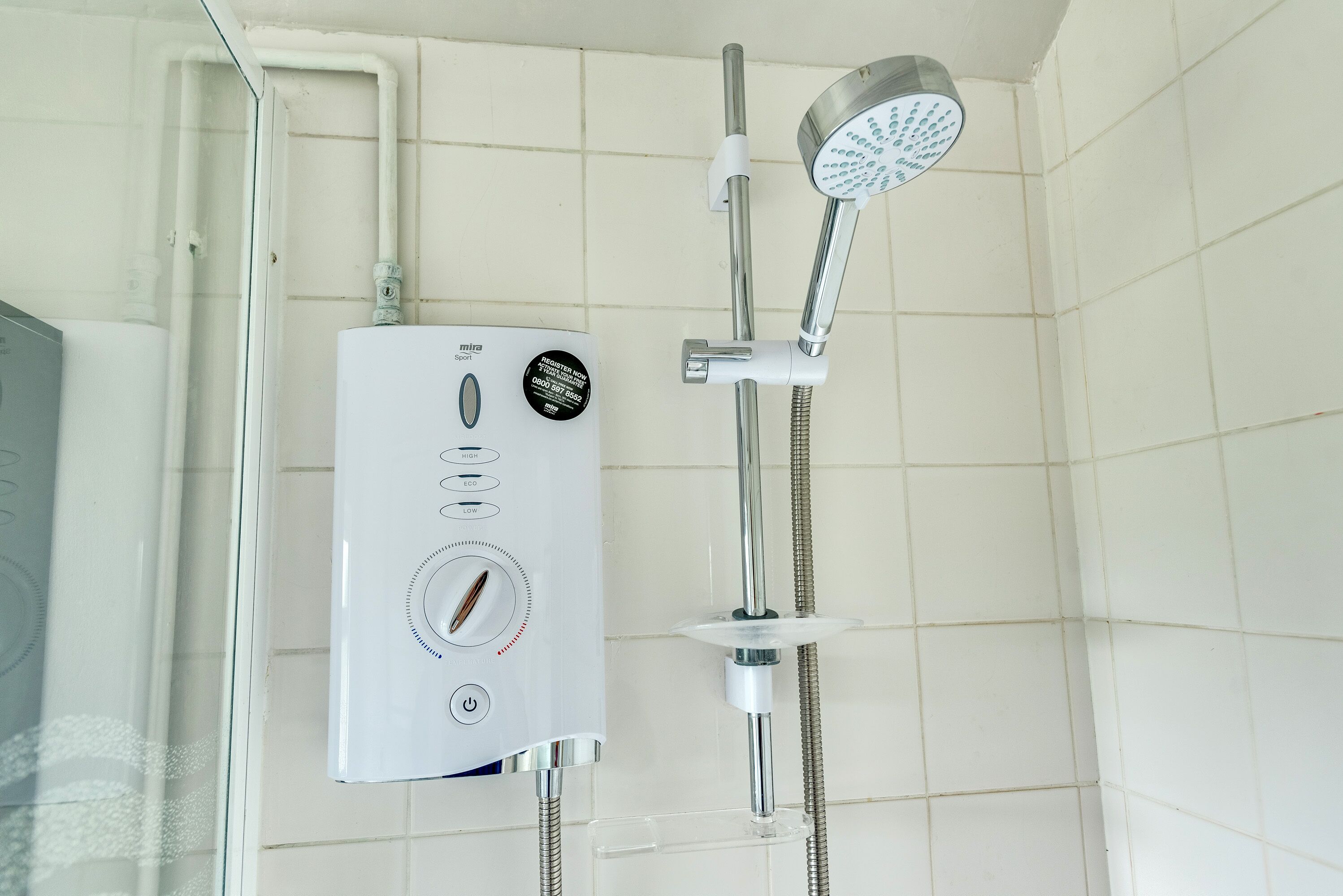 Une douche équipée d’un panneau de commande, d’un pommeau de douche à main et d’un pommeau de douche fixé au mur.