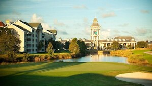 Ein Golfplatz mit Teich, Clubhaus und einem Turm.