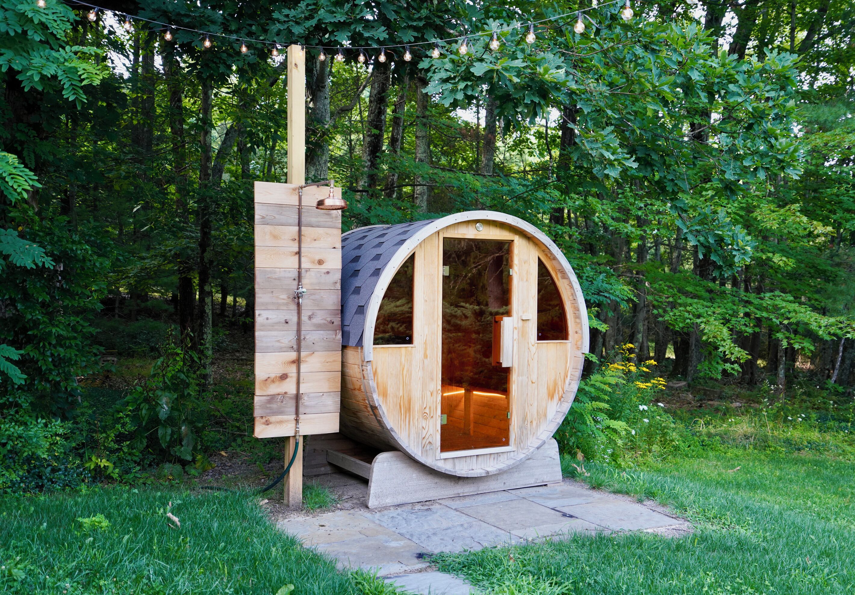 A wooden barrel-shaped structure with a door, a small porch, and a light fixture above.
