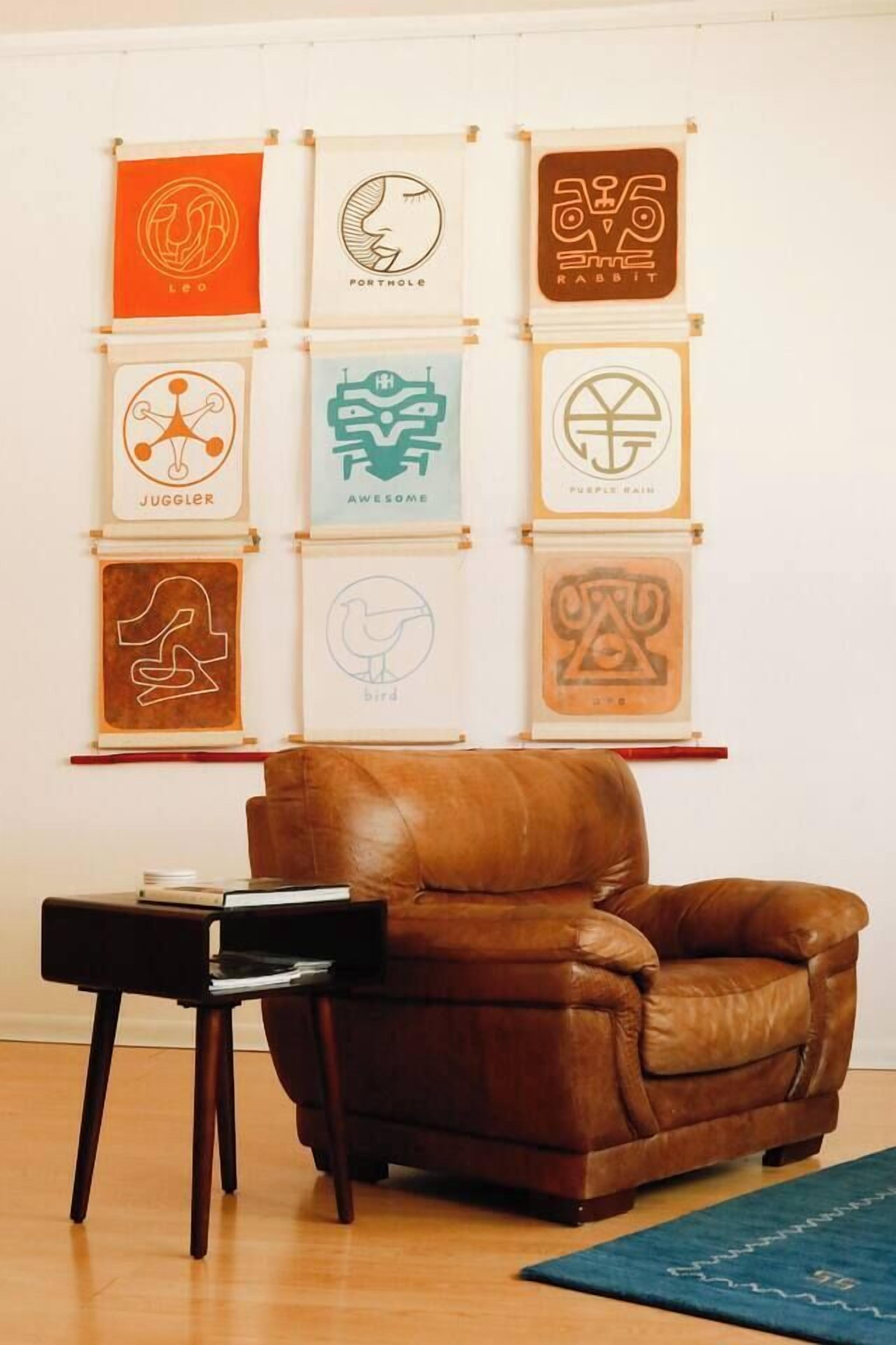 A brown leather armchair in a room with a wooden floor, a small black table, and a blue rug.