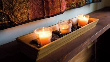 A wooden tray with three lit candles on a wooden surface.