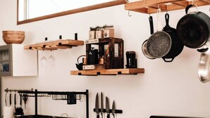 Eine Küche mit Holztischplatte, hängenden Töpfen, einer Kaffeemaschine und einem Messerbrett.