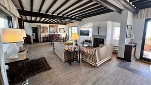 A spacious living room with wooden flooring, striped sofas, a fireplace, and a television. - Penthouse Piccadilly with Jacuzzi (Lido di Camaiore)