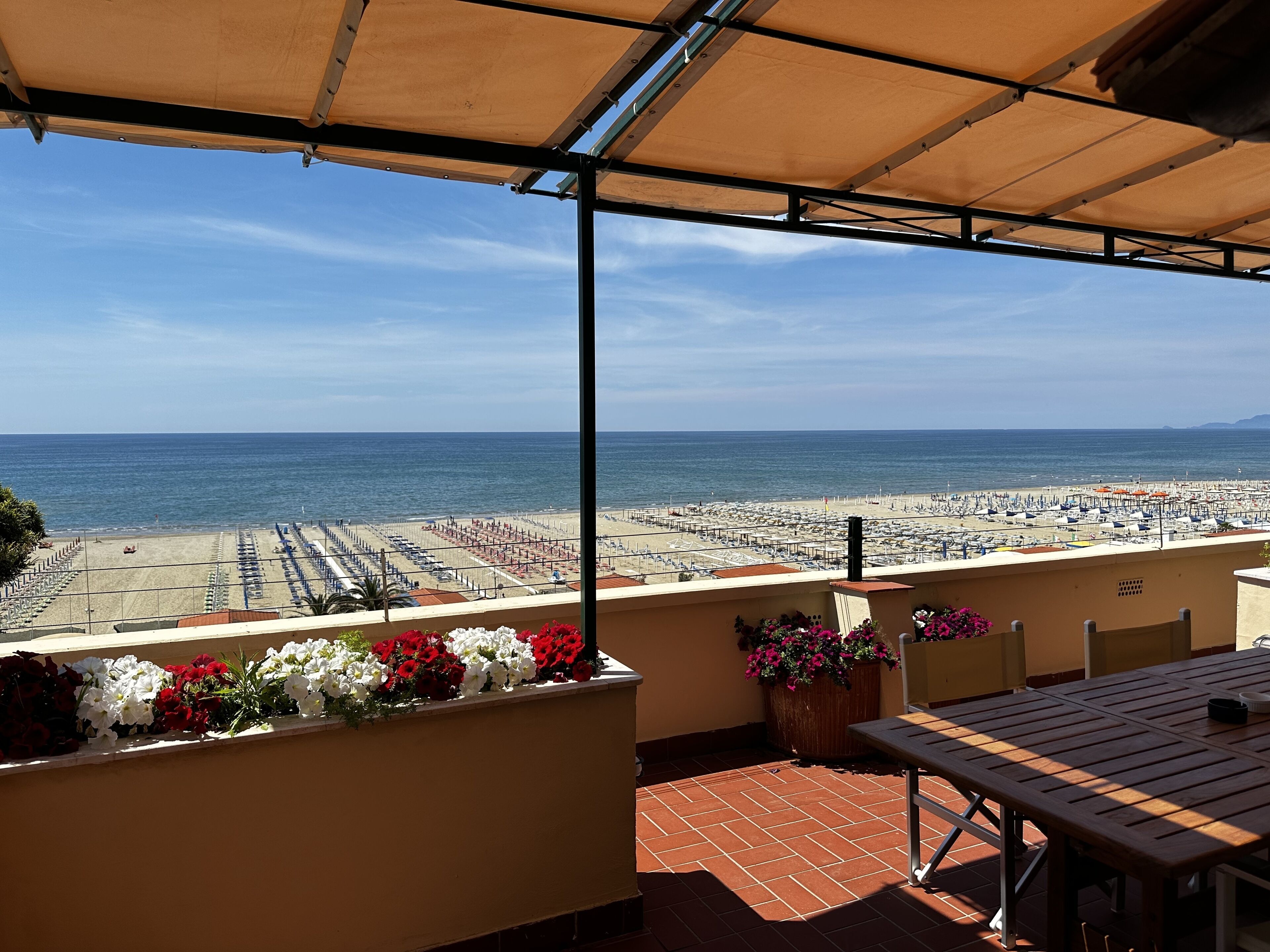 A terrace with a view of a beach and the sea.