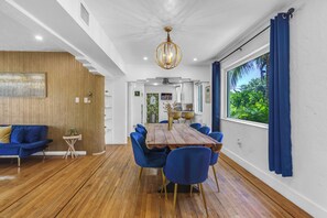 Un espace repas avec une table en bois, des chaises bleues et un lustre.