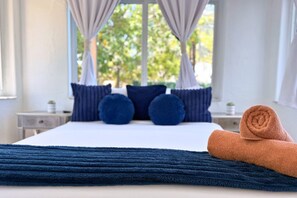 Un lit avec une couverture bleue, des oreillers et une serviette enroulée.
