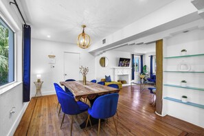 A modern dining area with a wooden table, blue chairs, and a hanging light fixture.