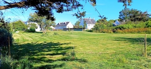 A well-maintained grassy lawn with a few trees and a row of houses in the background. - TY BRAZ – Very large house, a 3-minute walk from the beach (on the Baie de Quiberon side) (Saint-Pierre-Quiberon)
