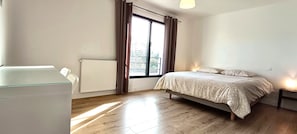 Une chambre à coucher avec un lit, un radiateur, une fenêtre avec des rideaux et une table de chevet.