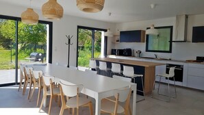 A modern kitchen with white cabinetry, a central island, and a dining area with white chairs. - TY BRAZ - Very large house 3 minutes walk from the beach (Baie Quiberon side) (Saint-Pierre-Quiberon)