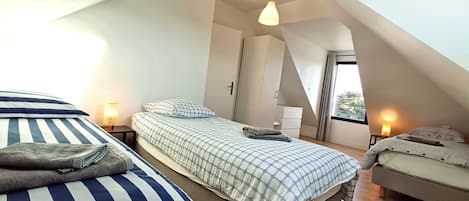 A bedroom with two beds, a window, and a door.