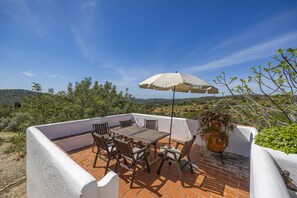 Enjoy al fresco dining on the terrace with a table and chairs, surrounded by lush greenery and a scenic view.