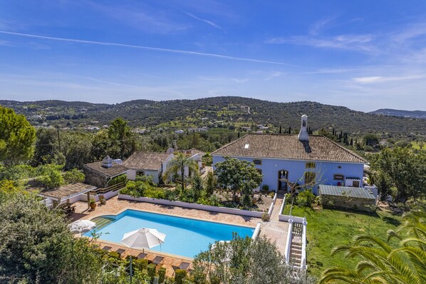 Relax in a serene villa surrounded by lush greenery and rolling hills, with a pool and picturesque views of the countryside.