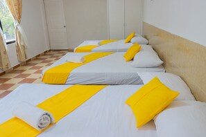 A hotel room with two beds, each with white linens and yellow accents.