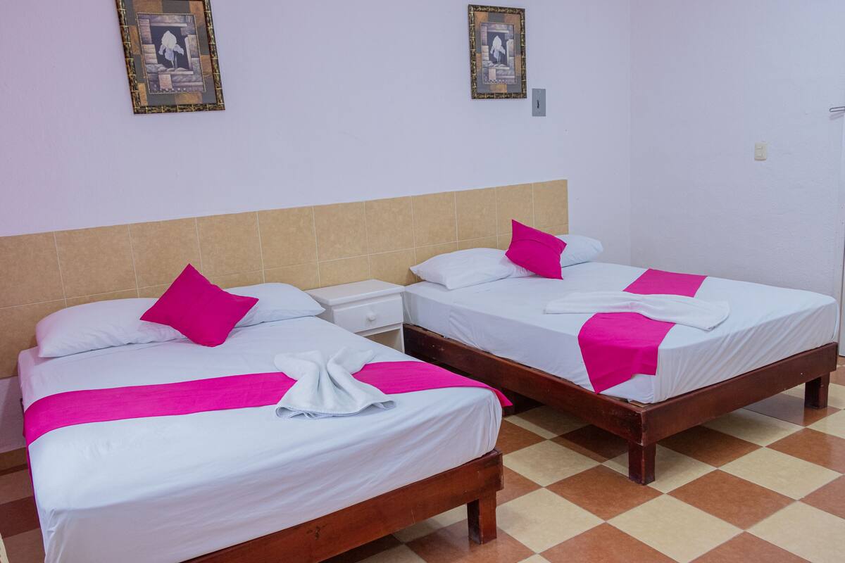 Two single beds with wooden frames, white bedding, and pink accents.
