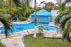 Una piscina con diseño de azulejos azules y blancos, rodeada de palmeras y un pequeño césped.