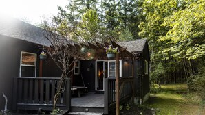 A cabin with a wooden deck, a porch, and a small garden area.