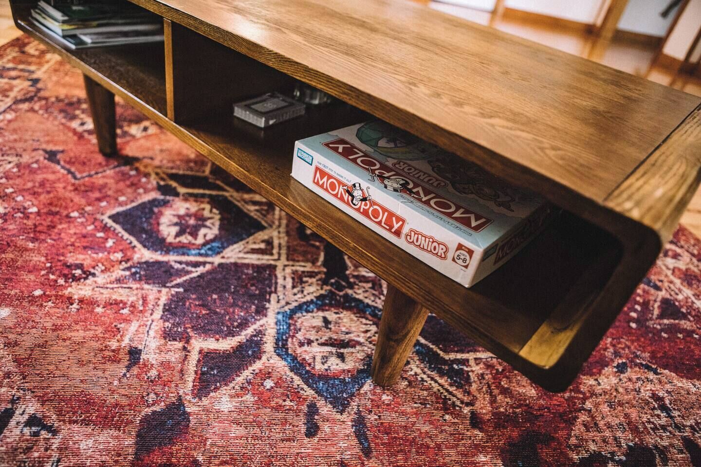 Una mesa de centro de madera con una caja del juego Monopoly Junior.