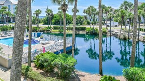 A pool area with a dock, surrounded by palm trees and a clear blue sky. - 97 Steps to Beach,  Beautiful Condo, Balcony Sleeps 5 (Santa Rosa Beach)