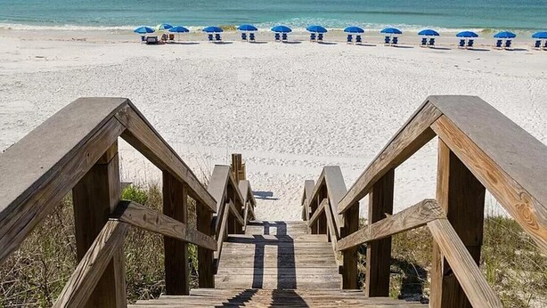A wooden staircase leading to a beach with blue umbrellas. - 97 Steps to Beach,  Beautiful Condo, Balcony Sleeps 5 (Santa Rosa Beach)