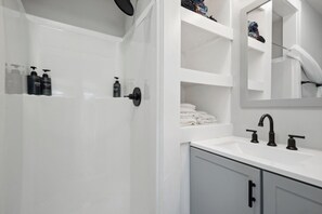 A modern bathroom with a white sink, black faucets, and a mirror above the counter. - 3-bedroom cottage Gulfport Beach (Gulfport)