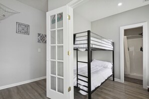 A bunk bed room with a white door, a shower area, and two framed wall decorations.