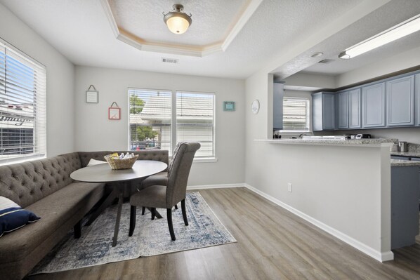 A modern kitchen with grey cabinets, a dining area with a round table and chairs, and a built-in island with a sink.