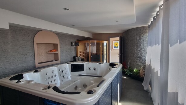 A modern bathroom with a large bathtub, stone wall accents, and a view of the outdoors. - Miga Hotel Airport (Isola di Capo Rizzuto)