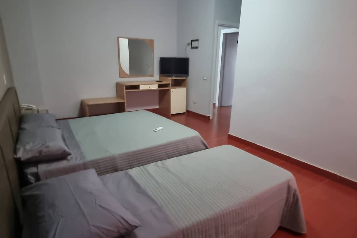 A hotel room with a bed, a desk with a computer, a TV, and a mirror.