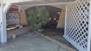A restaurant entrance with a sign reading "Ristorante - Pizzeria," a palm tree, and a lattice fence. - Miga Hotel Airport (Isola di Capo Rizzuto)